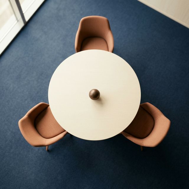 Overhead view of a round table with three chairs and a single ball