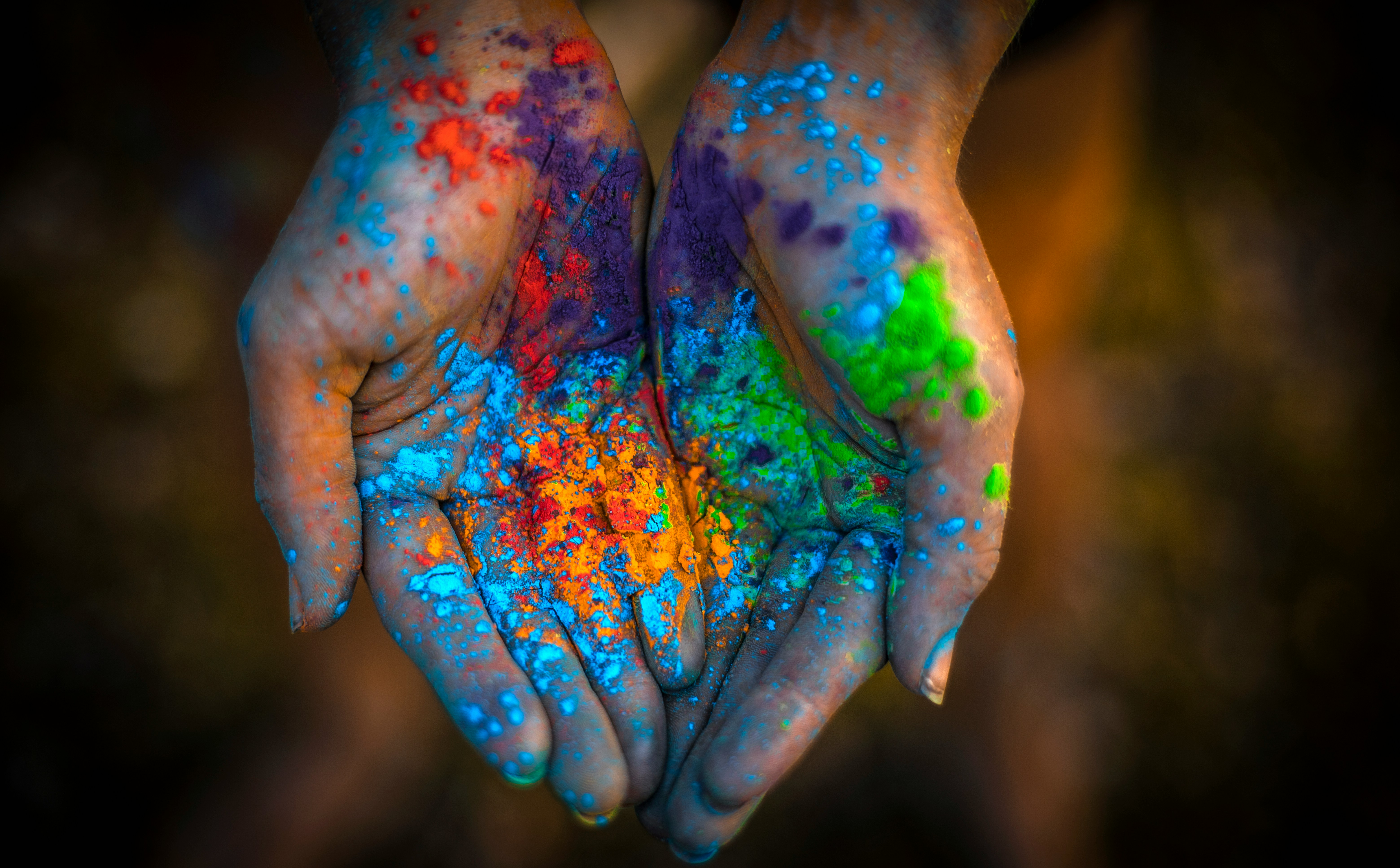 a pair of hands covered in colored powder